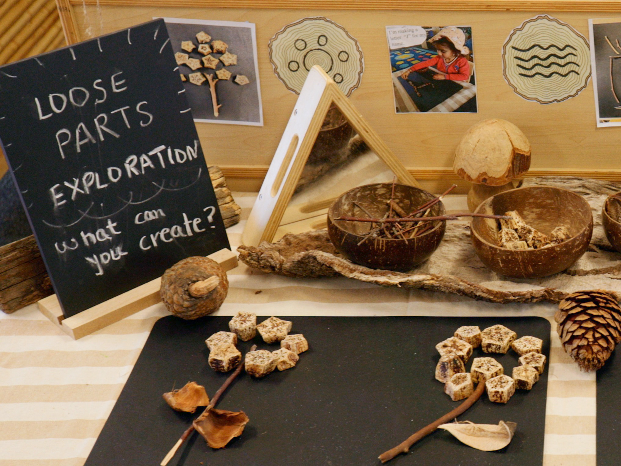 Natural materials laid out on a table next to a sign that says 'Loose parts exploration: what can you create?'