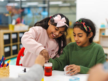 Two girls smiling doing science experiment with coloured liquid