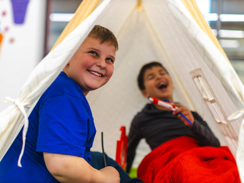Boys playing inside teepee tent laughing at holiday program