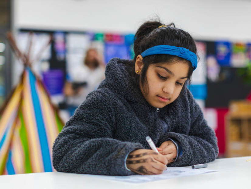 Girl sitting at table doing her homework at OSHC 826x620