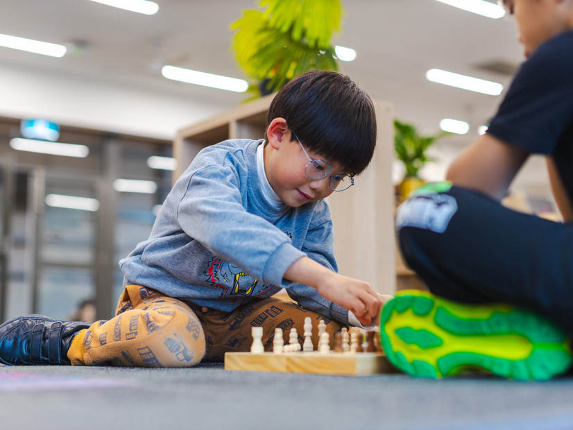 Two boys playing chess at outside school hours care