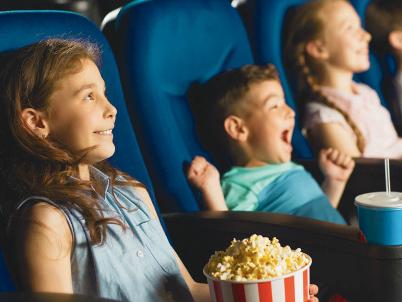 Kids with popcorn and drinks enjoying watching a movie in a cinema